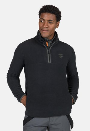 Zwart fleece pullover met een kwart rits, voorzien van een hoge kraag, grijze accenten en een logo op de borst. Gelaagd, warm en licht ontwerp.