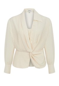 Blouse crème avec un motif rayé texturé, présentant un col, un détail noué à l'avant et des manches longues avec des poignets boutonnés.