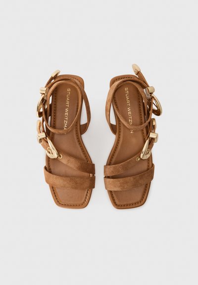 Bruna mockaskinnsandaler med flera remmar, fyrkantig tå och detaljer i guld. Platt sula med en slät, tanfärgad foder.