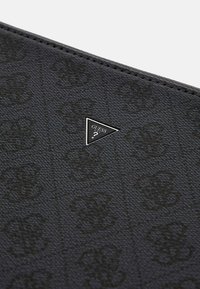 Black textured synthetic material featuring a subtle pattern. Silver triangular logo plaque with "GUESS USA" in the center.