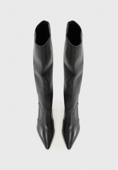 Knee-high, terava nina ja siledast mustast nahast saapad. Omab väljakujundatud disaini ja minimaalse õmbluse detailidega.