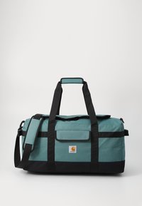 Sac de sport teal et noir en tissu durable. Comprend des poignées de transport doubles, une bandoulière réglable et une fermeture supérieure zippée.