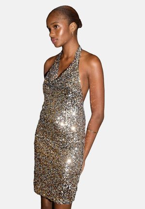 Vestido de cuello halter cubierto de lentejuelas, con tonos dorados y plateados. Diseño ajustado al cuerpo, con una textura suave y un acabado ligeramente brillante.