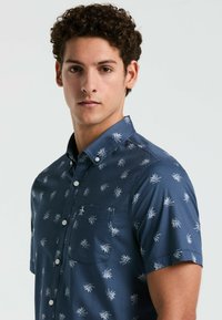 Korte mouwen overhemd met knopen in marineblauw met een wit bladerenpatroon, voorzien van een borstzak en een zachte stoffen textuur.