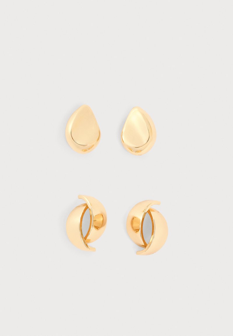 Deux paires de boucles d'oreilles en or brillant, l'une en forme de goutte et l'autre en forme de croissant, présentées sur un fond clair.