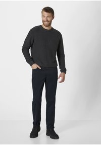 Dark gray knitted sweater with a round neckline, paired with navy chinos and black lace-up boots, displayed on a male model in a neutral backdrop.