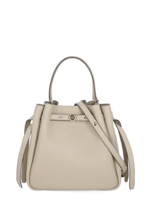 Sac à main en cuir beige avec anses supérieures, une bandoulière détachable et un petit logo circulaire doré sur la sangle avant.