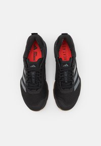 Scarpe da ginnastica nere con tomaia in mesh, con strisce e testo grigi. Fodera interna rossa, lacci neri e suola in gomma.