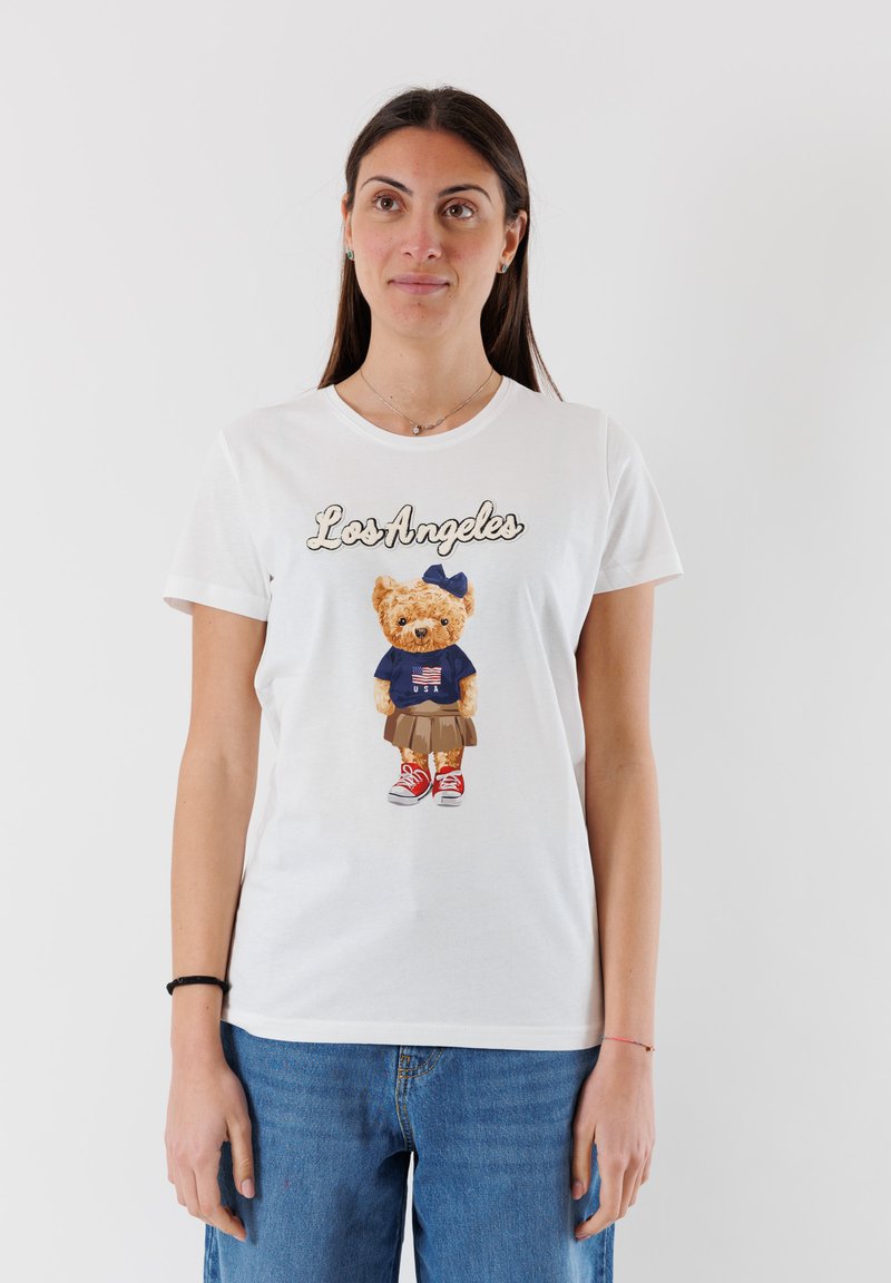 T-shirt in cotone bianco con una grafica di un orso in camicia blu con una bandiera americana, che indossa una gonna e sneaker rosse, con la scritta "Los Angeles".