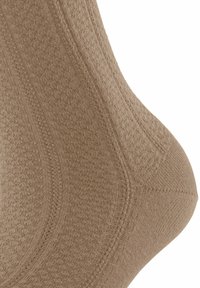 Beige Knöchel-Socke mit strukturiertem Material, ausgestattet mit einem gerippten Bündchen und verstärktem Zehenbereich. Glattes Gewebe mit dezenten, gewebten Musterdetails.