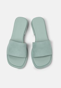 Mint green slide sandals with a soft, suede strap and a smooth rubber sole. Square-shaped design with rounded edges. Unique texture detail.