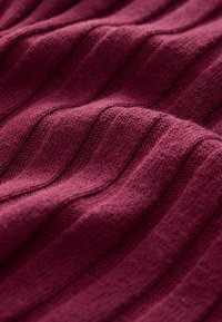 Burgundy stickad tyg med ribbad textur, med växlande upphöjda och platta ränder för visuell och taktil intresse.
