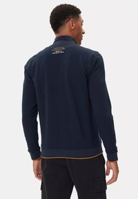 Felpa navy con colletto alto, polsini e orlo a coste, caratterizzata da un logo ricamato in oro sul retro e un accento giallo a contrasto all'orlo.