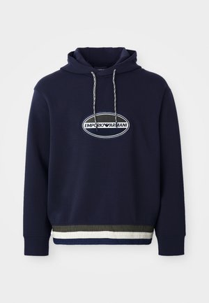 Hoodie bleu marine avec un logo brodé dans un patch ovale. Comprend une capuche avec cordon de serrage et un ourlet côtelé texturé avec des rayures contrastées.