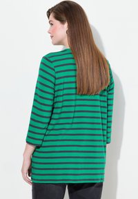 Grün und marineblau gestreiftes Langarmshirt mit lockerer Passform, abgerundetem Saum und seitlichen Schlitzen. Weicher, leichter Stoff.