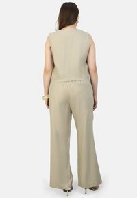 Beige linnen jumpsuit met wijde pijpen, een cropped top met een vierkante halslijn en subtiele steken aan de achterkant.