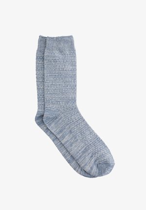 Világoskék kötött zoknik texturált mintával, ribbelt szegéllyel és sima lábujjal. Az anyag puhanak és vastagnak tűnik.