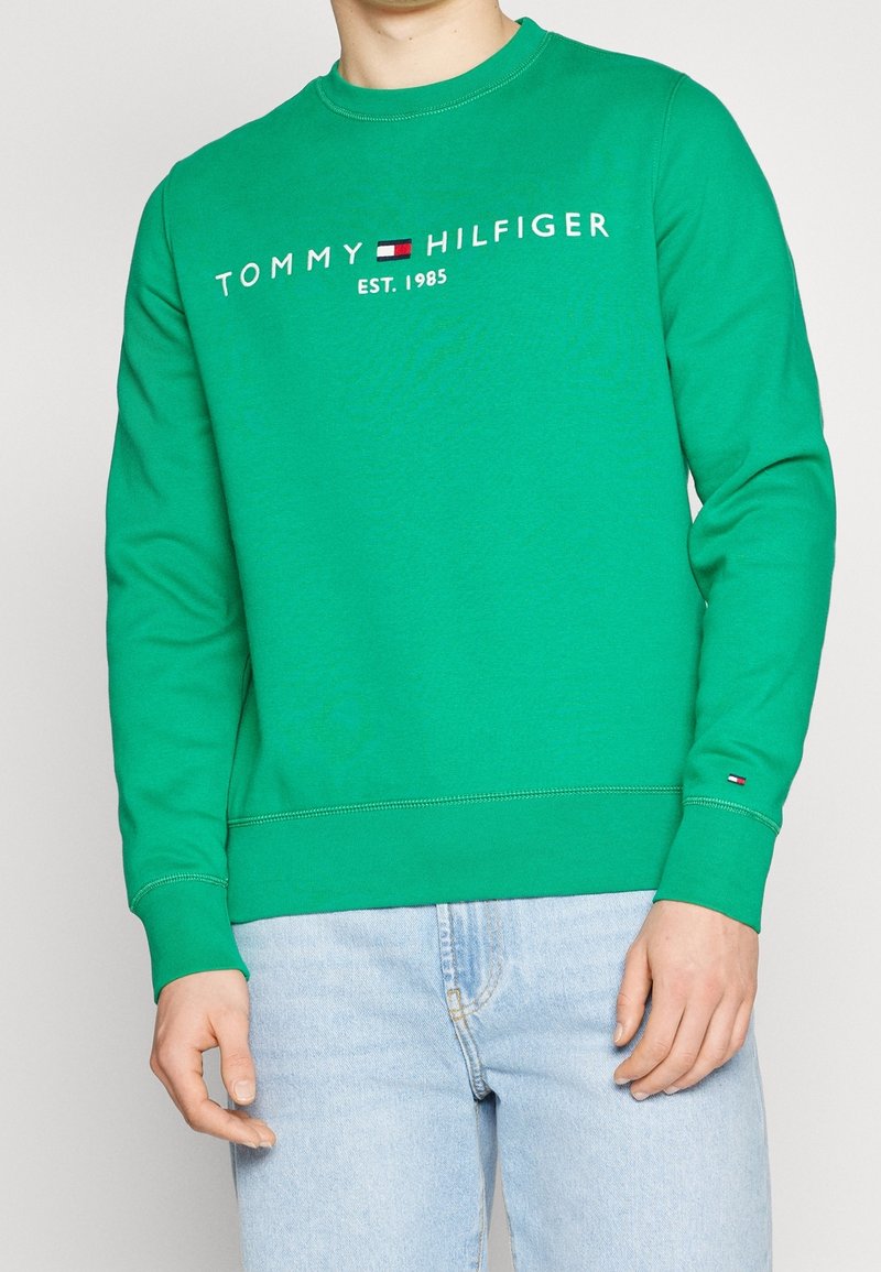 Felpa verde in cotone con scollatura a girocollo, con il logo "TOMMY HILFIGER EST. 1985" in bianco e rosso sul petto.