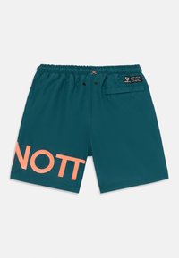 Shorts de banho turquesa feitos de um tecido leve, com uma grande impressão em coral "NOTT" na perna esquerda e uma cintura elástica.