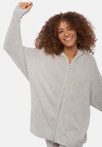 Sweat-shirt à capuche gris avec une coupe ample, des manches longues et une fermeture éclair intégrale à l'avant. Texture douce et poignets côtelés pour un confort optimal.