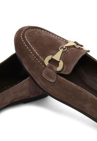 Mocassins en suede marron avec un accent doré et des détails de couture. Dotés d'une semelle plate et d'un design à bout arrondi.