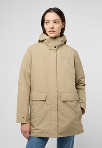 Veste parka beige avec une capuche, fermetures à pression, deux grandes poches avant et des poignets ajustables. Tissu lisse avec un léger éclat.