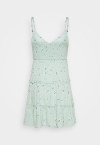 Mintgrön klänning med blommönster, flerlagad design, justerbara tunna axelremmar och texturerad bål. Lätt, avslappnad sommarstil.