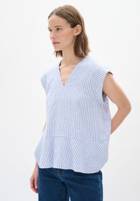 Prúhovaná modro-biela blúzka s výstrihom do V, krátkymi rukávmi a voľným strihom. Má rozšírený spodný lem a ľahkú textúru látky.