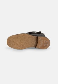 Zapato negro con una suela de corcho texturizado. La plantilla presenta un diseño circular y está grabada con "37" y los detalles de la marca.