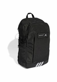 Mochila de tela negra con forma estructurada, parche con logo en la parte frontal, múltiples compartimentos, hebillas laterales y tres franjas blancas en la parte inferior.