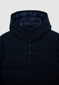 Giacca imbottita blu navy con colletto alto, cappuccio, zip frontale e tasca verticale sul petto, su uno sfondo chiaro e semplice.