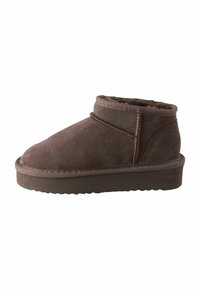 Braune Wildleder-Stiefeletten mit einem weichen Innenfutter, runder Zehenpartie, niedrigem Absatz und einer genähten Gestaltung entlang der Naht. Flache Gummisohle.