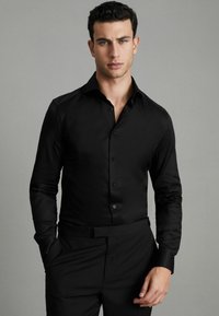 Cămașă neagră cu mâneci lungi, manșete cu nasturi și guler clasic. Fabricată dintr-un material neted, având un design ajustat.