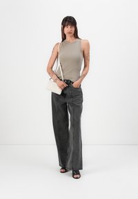 Beige ripset tanktop, høytlivs svarte denim vide bukser og svarte høyhælte sandaler. Akkuratert med en liten teksturert hvit håndveske.