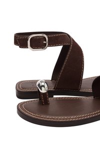 Brązowe zamszowe sandały o eleganckim designie, z paskiem na kostkę i srebrną klamrą, oraz gładką podeszwą z kontrastującymi detalami w szyciu.