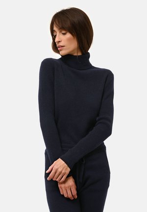 Pull à col roulé bleu marine avec texture côtelée, manches longues et coupe ajustée, doté d'une taille à cordon pour un ajustement réglable.