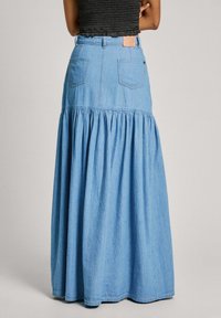 Ljusblå denim maxikjol med samlad nederdel, bakfickor och en vävd etikett på midjebandet. Slät struktur, rak skärning.