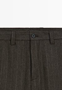 Donkergrijze wollen broek met een streepjespatroon, een vlakke voorkant, riemlussen en een zwarte knoopsluiting in de taille.