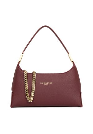 Donkerrode leren Lancaster Paris handtas met enkele handgreep en goudkleurige kettinkdetail aan de voorkant tegen een witte achtergrond.