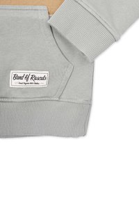Ljusgrå sweatshirt. Mjuk bomullsblandning, ribbade ärmslut och nederkant, känguruficka, har en vävd etikett med texten "Band of Rascals".
