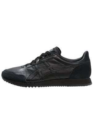 Czarny niski sneaker ze skóry i zamszu z czarnymi sznurówkami, teksturowaną podeszwą i subtelnym przeszyciem w postaci pasków po boku.