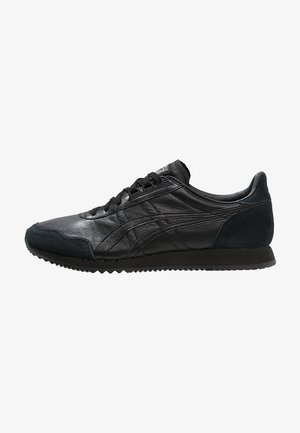 Baskets basses en cuir et suède noir avec des lacets noirs, une semelle texturée et un design subtil de rayures cousues sur le côté.
