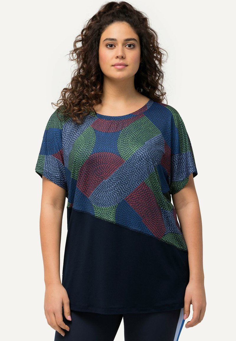 Camiseta de manga corta con una sección superior de patrón colorido en verde, azul y rojo sobre un fondo azul marino. Tejido suave, ajuste relajado.
