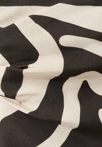 Tissu noir et blanc avec des formes abstraites et irrégulières et une texture lisse, légèrement froissé et plié.