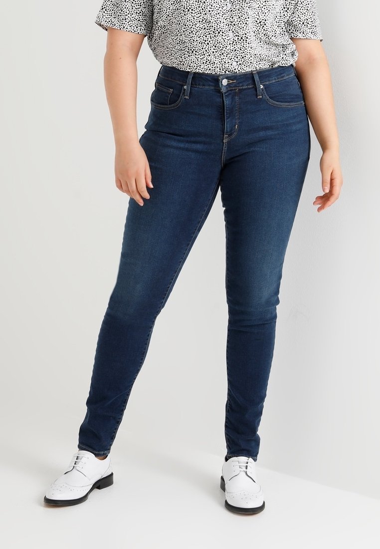 Jeans skinny azul oscuro con una textura suave, cinturilla alta y diseño clásico de cinco bolsillos, combinados con una blusa de manga corta con estampado.