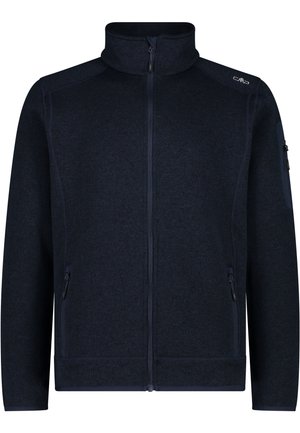 Hand in de ritssluiting van een donkerblauw getextureerd fleecejack gedragen over een zwarte broek.