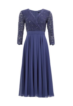 Pitkät purple-mekko, jossa on pits bodice ja paljetteja, V-mallisella kaula-aukolla ja kolmannen osan hihoilla. Hame virtaa vapaasti, valmistettu kevyestä kankaasta.