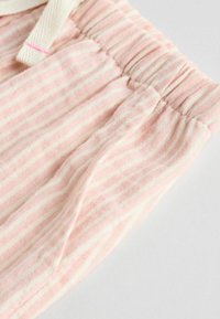 Tela de color rosa claro con rayas blancas, que presenta una cinturilla fruncida y un detalle de cordón. Textura suave, material liviano.