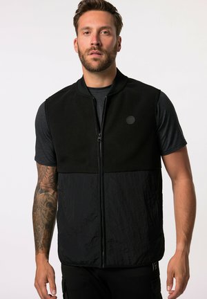 Gilet nero con zip frontale, caratterizzato da una parte superiore liscia e una sezione inferiore texturizzata. Include un logo tondo sul petto e un colletto a coste.