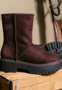 Stivaletti alla caviglia in suede bordeaux scuro con una suola spessa in gomma nera. Presenta una cucitura laterale e un dettaglio con il logo sul tallone. Suola testurizzata per una migliore aderenza.
